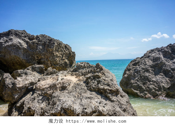蓝天白云下美丽的印尼巴厘岛美丽的大海和海滩，有大岩石
